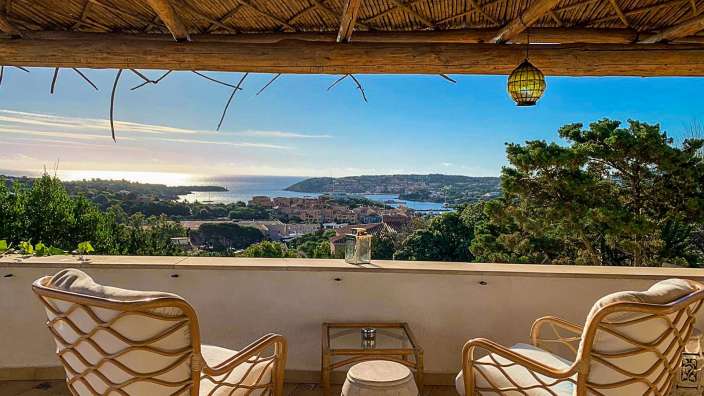 Zwei Stühle sitzen auf einem Balkon mit Blick auf das Meer