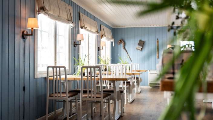 Ein Esszimmer mit blauen Wänden und weißen Tischen und Stühlen