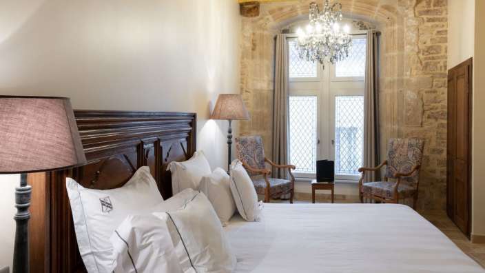 Ein Schlafzimmer mit einem Bett und zwei Stühlen und einem Kronleuchter