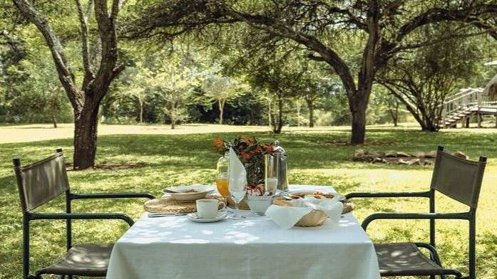 Ein Tisch mit einem weißen Tischtuch und zwei Stühlen im Gras