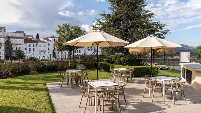 Eine Terrasse mit Tischen und Stühlen und Regenschirmen