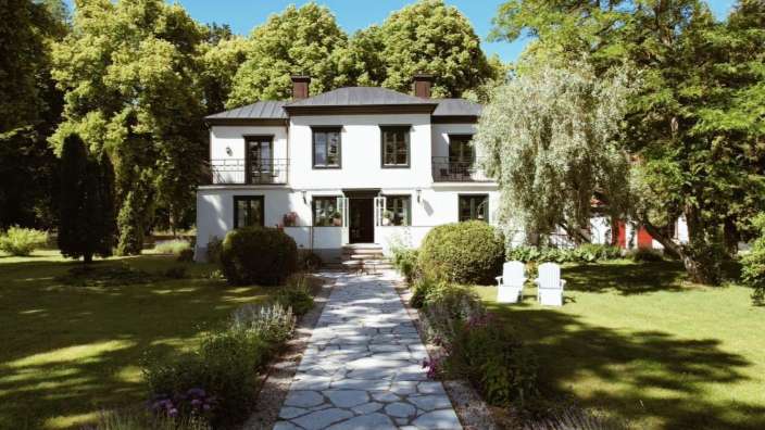 Ein weißes Haus mit einem schwarzen Dach und vielen Fenstern