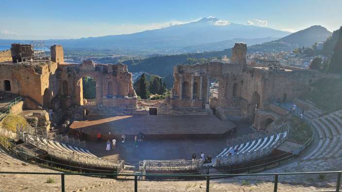 Amphitheater von Taormina  Menschen stehen in einem antiken Theater mit einem Berg im Hintergrund