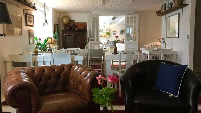 Ein Wohnzimmer mit einem braunen Ledersessel und einem schwarzen Stuhl