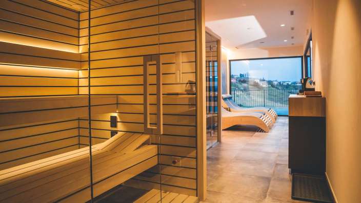 Ein Raum mit einer Sauna und Liegestühlen davor
