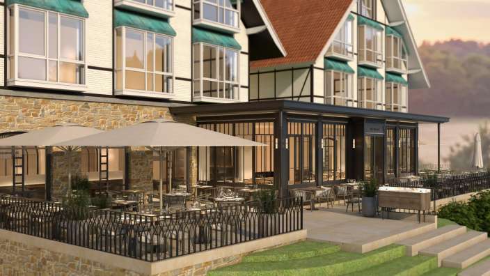 Ein Restaurant mit vielen Tischen und Sonnenschirmen vor einem Gebäude