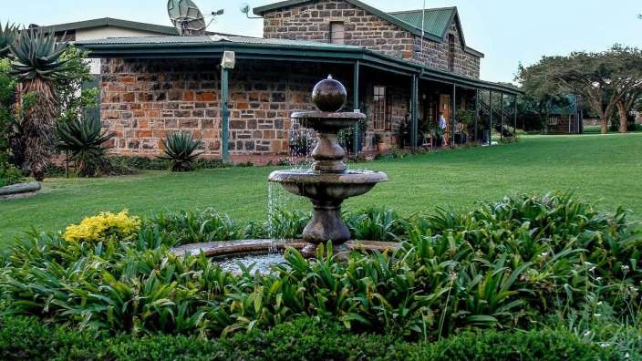 Ein Brunnen in einem Garten vor einem Steinhaus