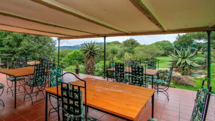 Tische und Stühle auf einer Terrasse mit Blick auf einen Golfplatz