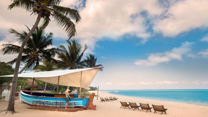 Ein blaues Boot mit einer Bar darauf sitzt am Strand