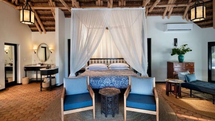 Ein Schlafzimmer mit einem Himmelbett und zwei Stühlen