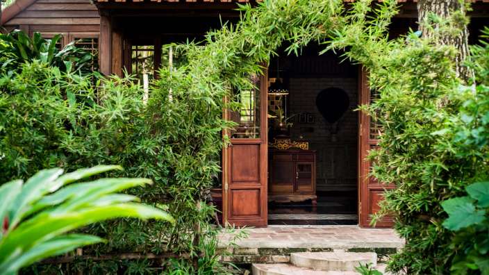 Ein kleines Holzhaus mit einem roten Dach umgeben von Bäumen