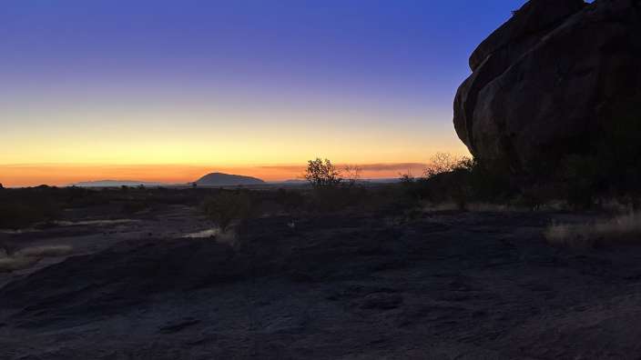 Ein Sonnenuntergang in der Wüste mit einem großen Felsen im Vordergrund