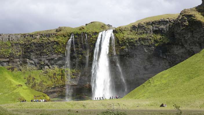 Eine Gruppe von Menschen steht vor einem Wasserfall