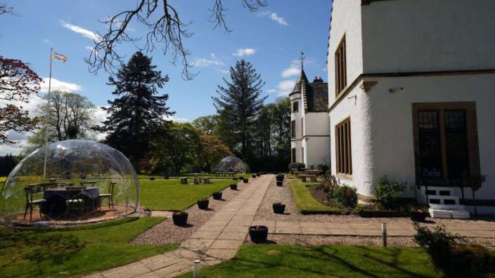 Ein weißes Gebäude mit einem Tisch und Stühlen in einer Glaskuppel