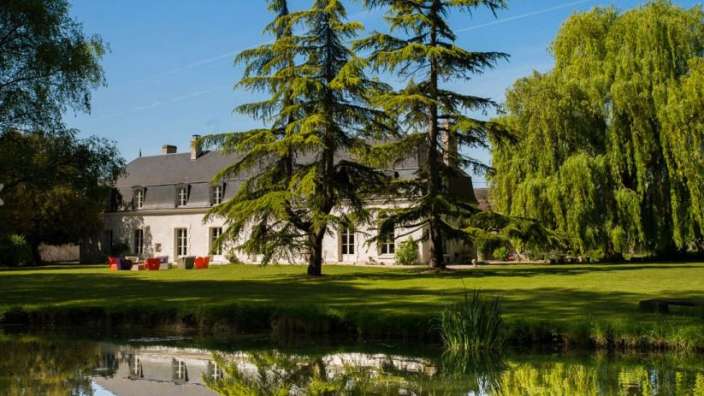 Ein großes weißes Haus steht neben einem Teich