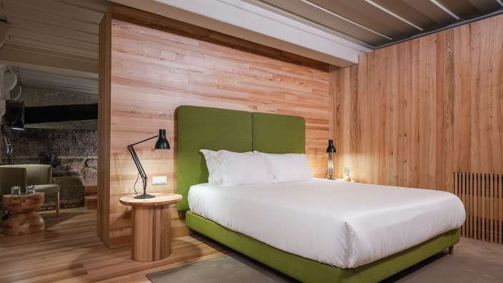 Ein Schlafzimmer mit Holzwänden und einem grünen Bett