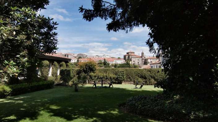 Ein Garten mit Bäumen und Stühlen und einer Stadt im Hintergrund