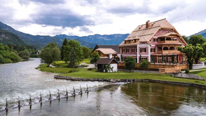 Ein großes rosa Haus steht am Ufer eines Flusses
