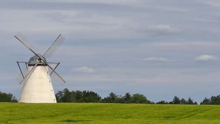 Eine weiße Windmühle steht auf einem grünen Feld