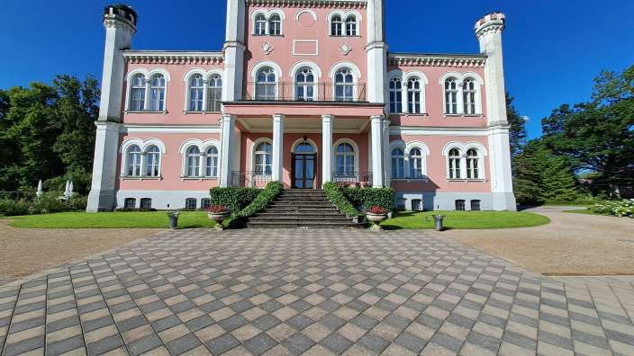 Ein großes rosa und weißes Gebäude mit einem Balkon