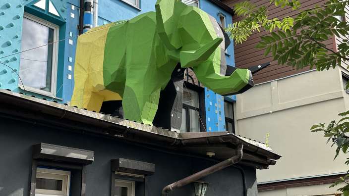 Eine grüne und gelbe Skulptur eines Elefanten auf dem Dach eines Gebäudes