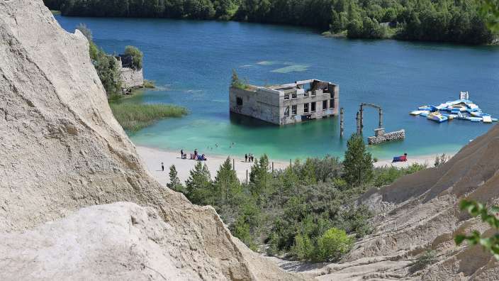 Eine Gruppe von Menschen steht an einem Strand in der Nähe eines Sees