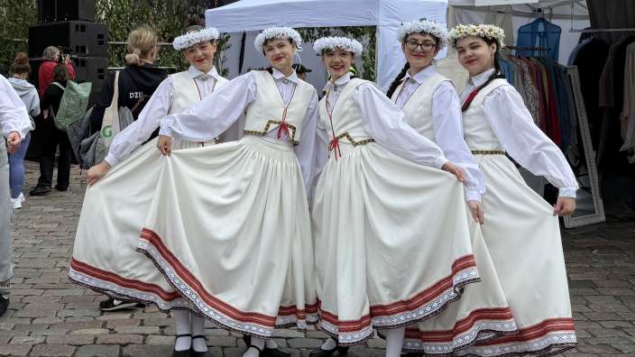 Eine Gruppe von Frauen in traditionellen Kostümen posiert vor einem weißen Zelt