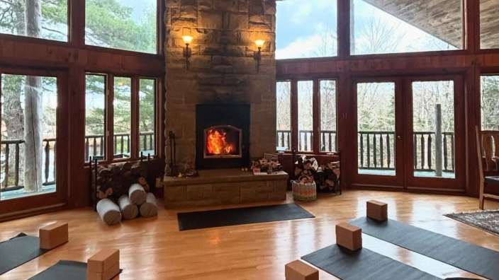 Ein großer Raum mit Yogamatten und einem Kamin