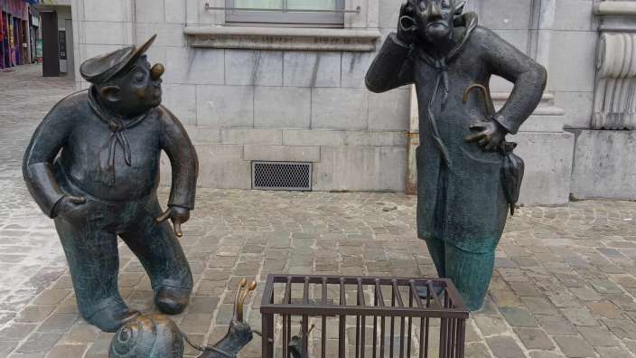 Eine Statue eines Mannes, der neben einer Schnecke in einem Käfig steht
