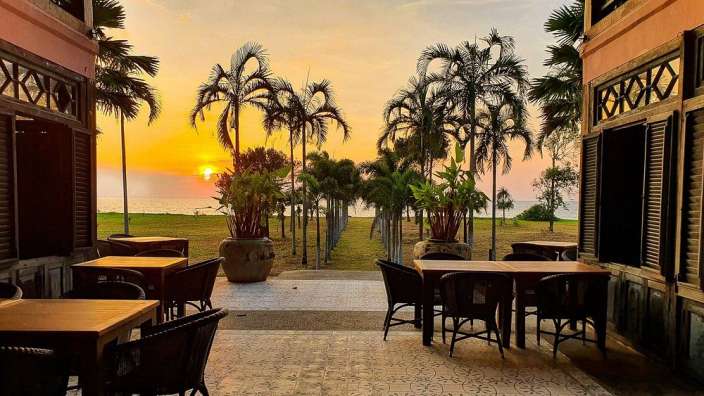 Tische und Stühle auf einer Terrasse mit Blick auf das Meer bei Sonnenuntergang