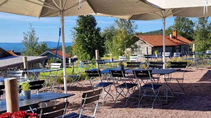 Tische und Stühle stehen unter Regenschirmen in einem Garten