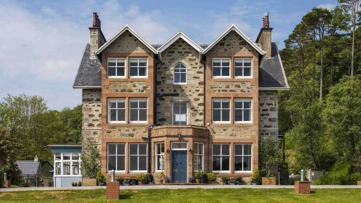 Ein großes Steinhaus mit vielen Fenstern und einer blauen Tür