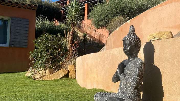 Eine Statue eines buddhas sitzt auf einem grünen Rasen