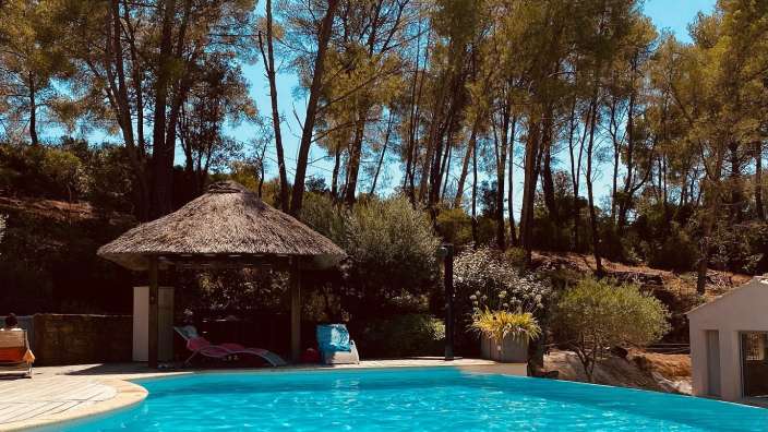 Ein Swimmingpool mit einem Strohpavillon im Hintergrund