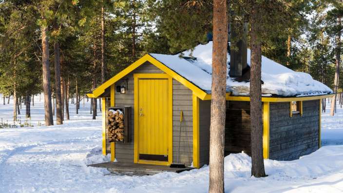 Ein kleines Haus mit einer gelben Tür inmitten eines schneebedeckten Waldes