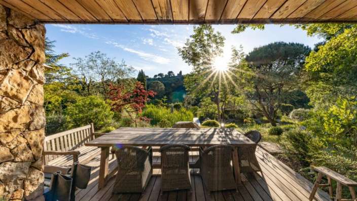 Die Sonne scheint durch die Bäume auf einem Holzdeck