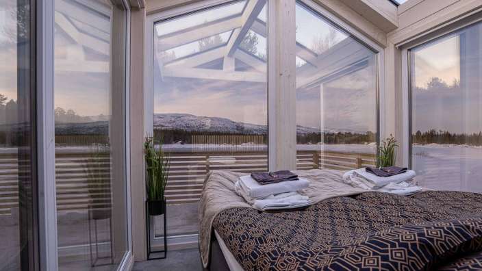 Ein Schlafzimmer mit einem Bett und vielen Fenstern