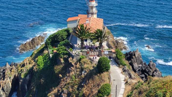 Cudillero Ein Leuchtturm sitzt auf einer Klippe über dem Ozean