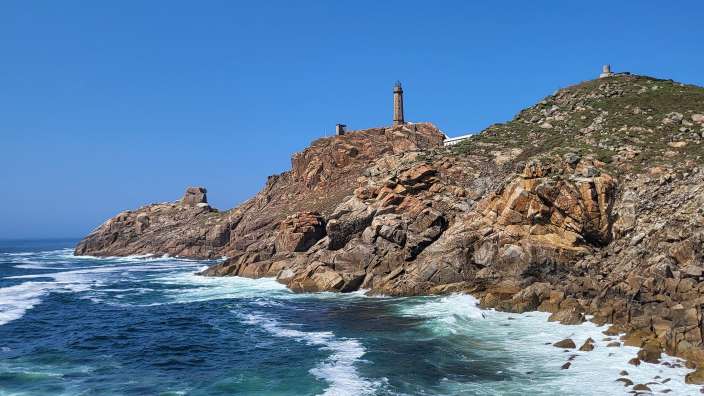 Costa da Morte Eine felsige Küste mit einem Leuchtturm in der Ferne