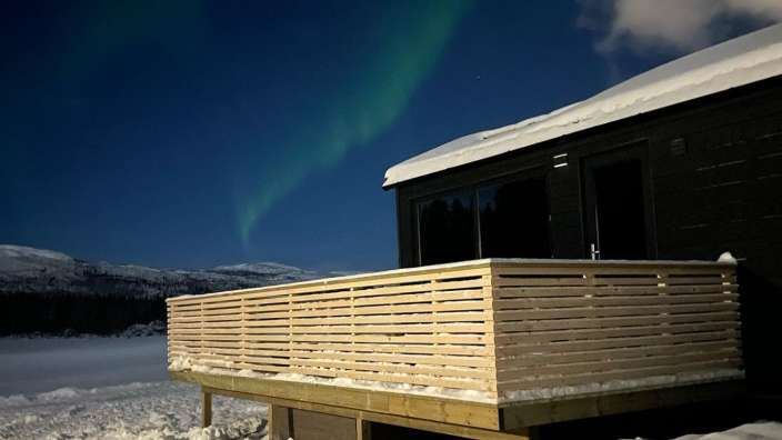 Das Nordlicht scheint über einem schneebedeckten Haus