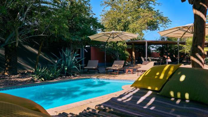 Ein Swimmingpool mit Liegestühlen und Sonnenschirmen umgeben
