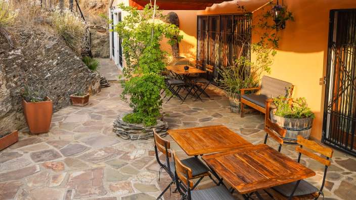 Eine Terrasse mit Holztischen und Stühlen und einem Dach
