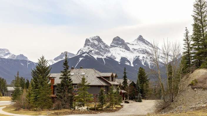 Ein großes Haus steht auf einem Hügel mit Bergen im Hintergrund