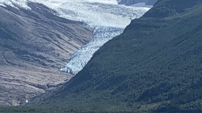 Ein Boot schwimmt auf einem See mit einem Gletscher im Hintergrund