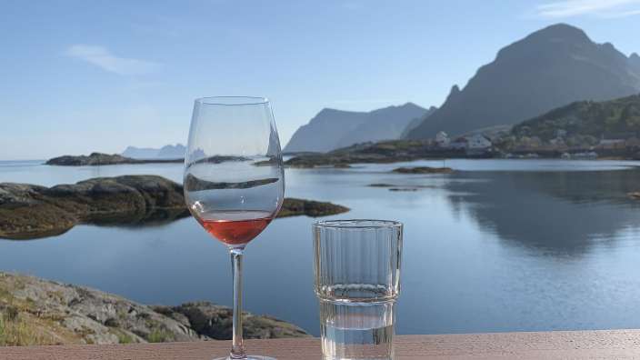 Ein Weinglas und ein Glas Wasser auf einem Balkon mit Blick auf den Ozean