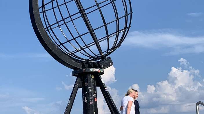 Eine Gruppe von Menschen steht vor einer großen Metallkugel