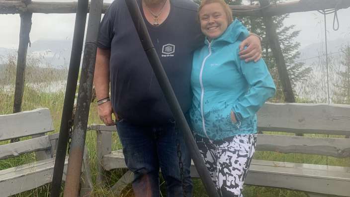 Ein mann und eine frau posieren neben einem lagerfeuer und einer bank