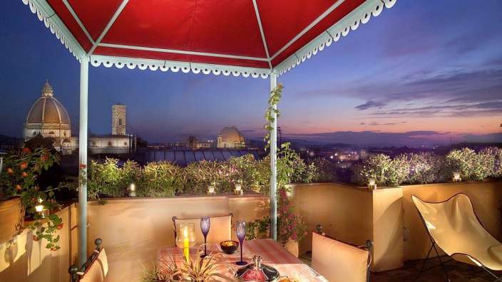 Eine Terrasse mit einem Tisch und Stühlen und einem roten Zelt