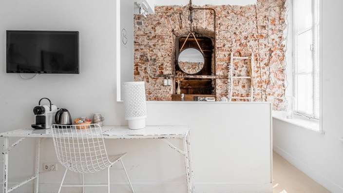 Ein weißer Schreibtisch mit einem weißen Stuhl und einem Fernseher an der Wand