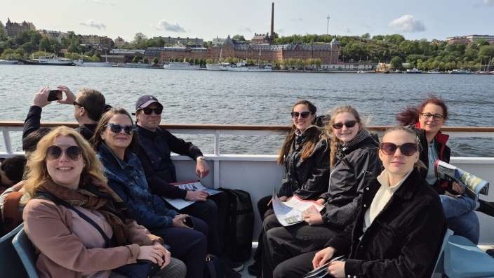Eine Gruppe von Menschen sitzt auf einem Boot und schaut auf das Wasser